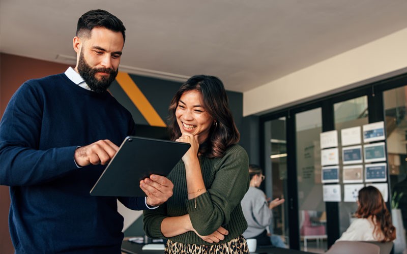We’ve been where you are, and we know how to help you navigate the landscape and choose the best investments. Smiling business professionals on tablet device in office