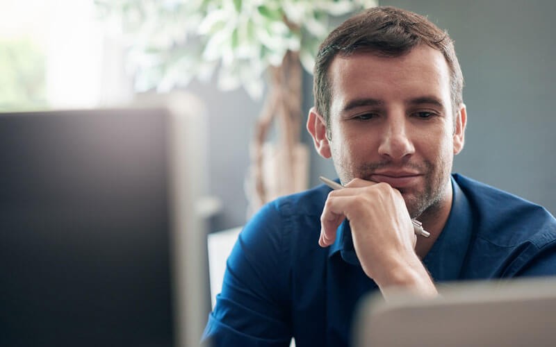 Close up of thinking businessman in front of laptop and desktop computer