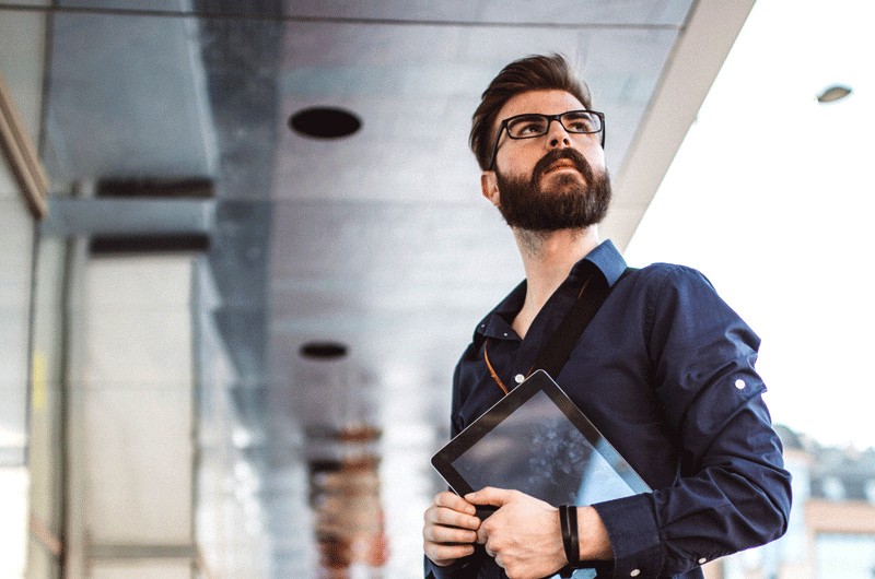 Business man looking up for ideas while holding tablet device