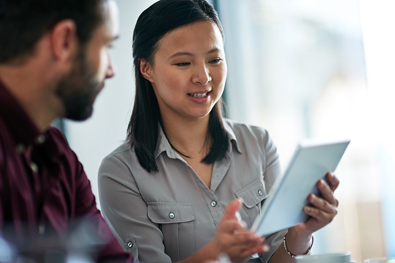 Businesswoman sharing data on tablet computer with colleague 
