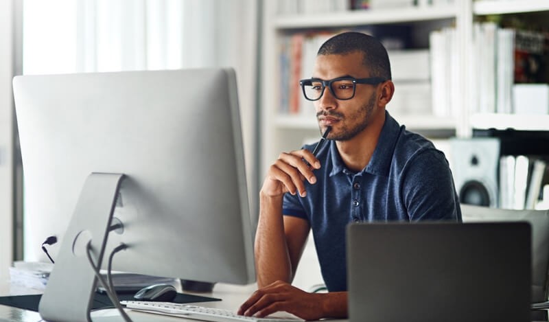 Remote worker in home office with desktop and laptop computer