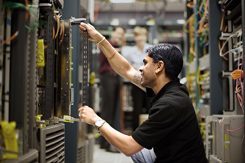 Integrate storage, data networking and network services across physical, virtual, and cloud environments. IT admin installing rack mountable server in data center