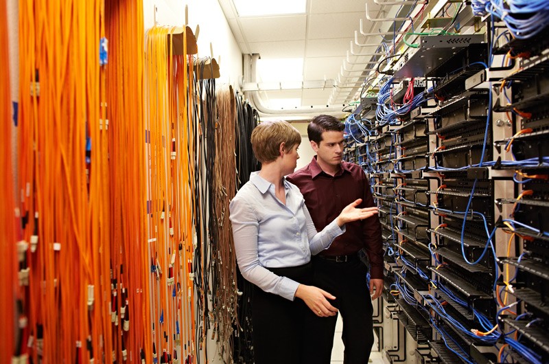 Cisco network solutions One IT worker assessing another in server room.