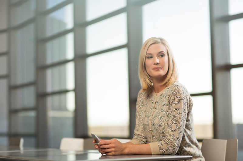Smart net total care Attractive woman sitting in room with large windows holding smart phone.
