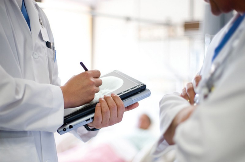 Doctors discuss patient info over tablet computer.