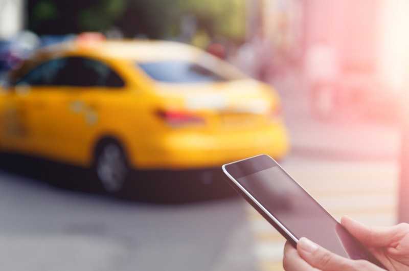 Manage your switching and access points. Woman on smart phone with taxi in background.