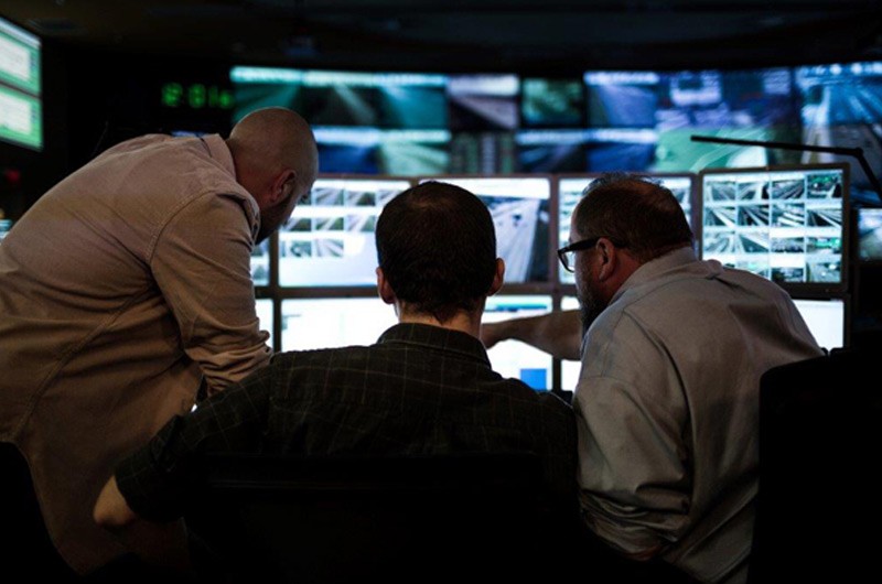 Build a more efficient data center. Three IT workers looking at multiple monitors.