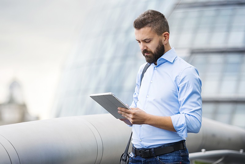 DocuSign is the most reliable electronic signature software on the market. Businessman using DocuSign electronic signature software on tablet computer while walking across bridge