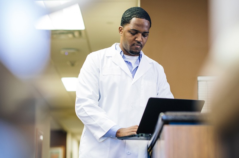 Doctor typing on black laptop device