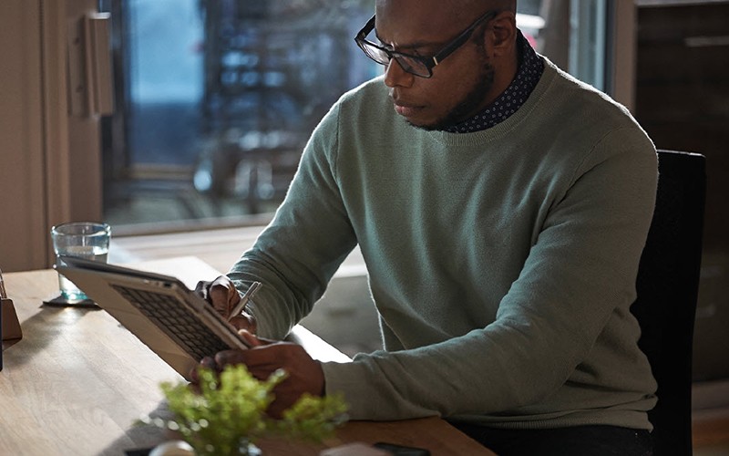 Simplification de la surveillance et de la gestion Man using stylus to write on his laptop