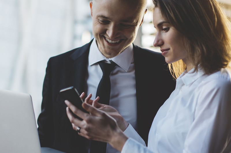 Symantec Endpoint Protection 14 Business man and woman looking at content on smart phone.