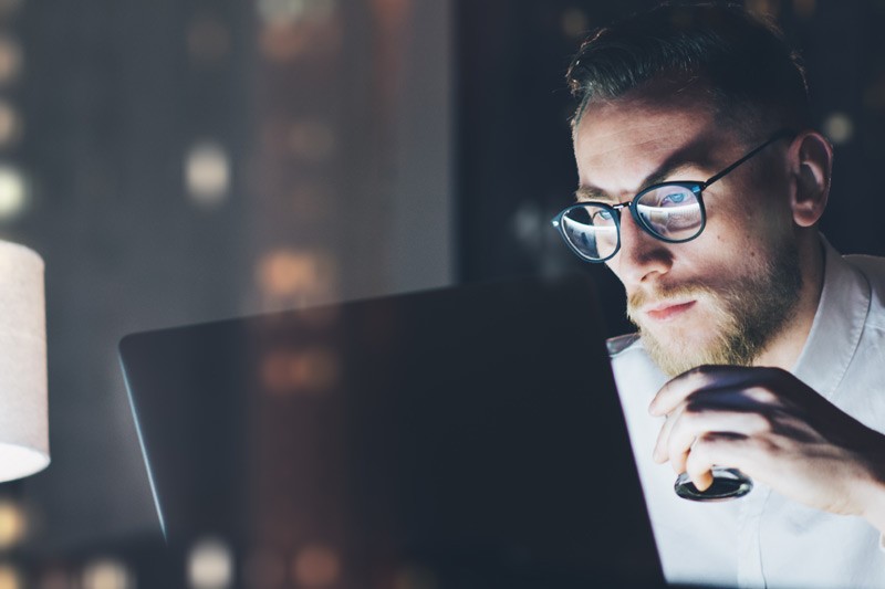 Symantec Protection Business man with glasses working late in office looking at laptop