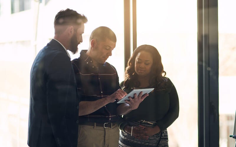 Three people looking over tablet device