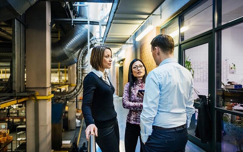 Expertise to minimize disruption Management team discusses business requirements in factory hallway
