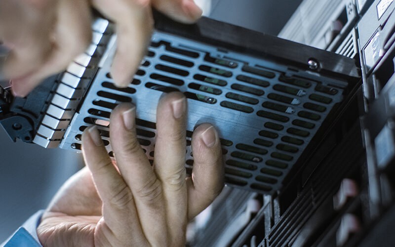 Enhanced backup and disaster recovery IT engineer installing new hard drive to server rack