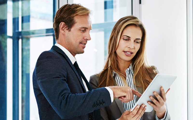 We’ll help you navigate the right combination of public and private cloud Two business professionals on tablet discussing cloud strategy