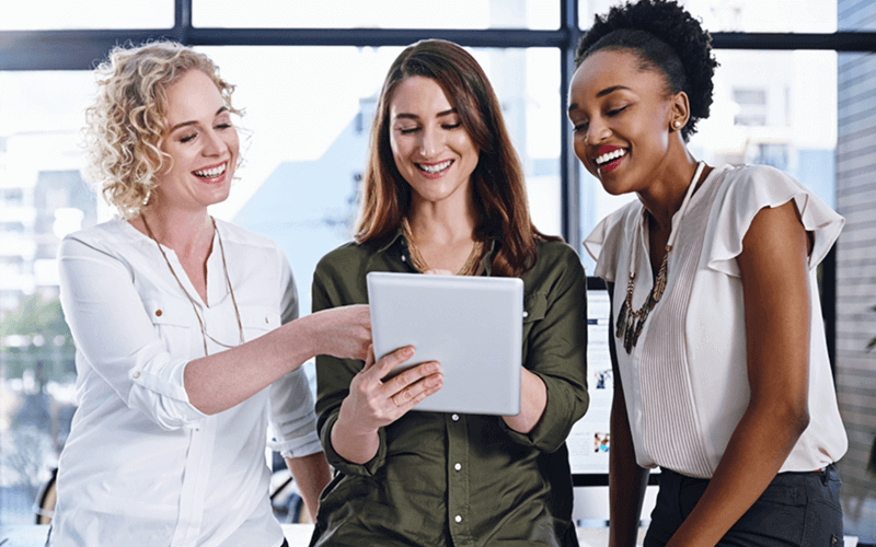 Understand how to maximize benefits and minimize risk Three business women in front of open office window on tablet device