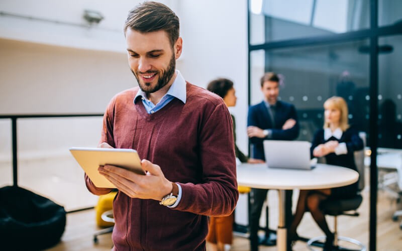 smiling-man-on-tablet-device-in-office smiling-man-on-tablet-device-in-office