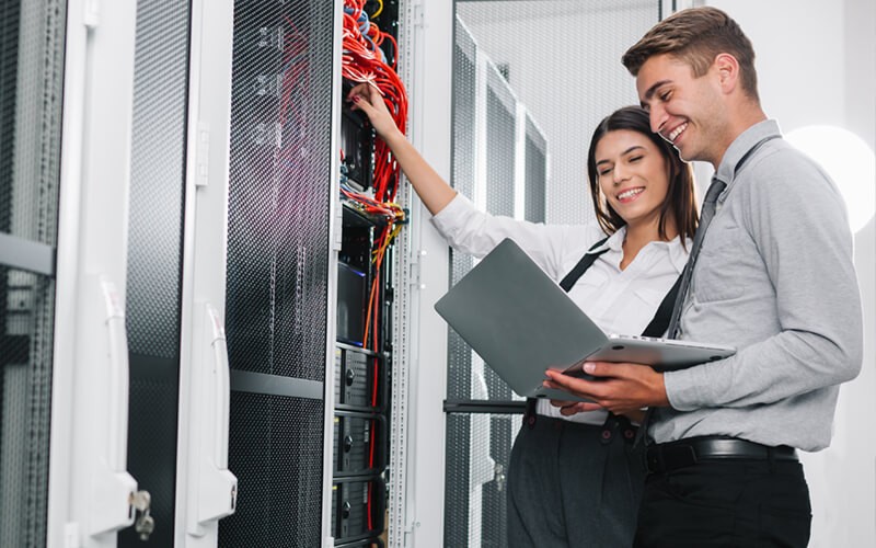 Simplify your journey to true IT transformation Two IT engineers work in data center with laptop computer