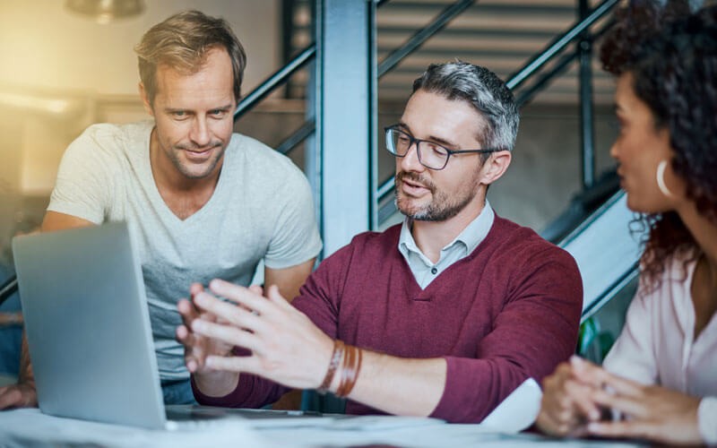 We customize the onboarding process Three business professionals discuss over laptop device