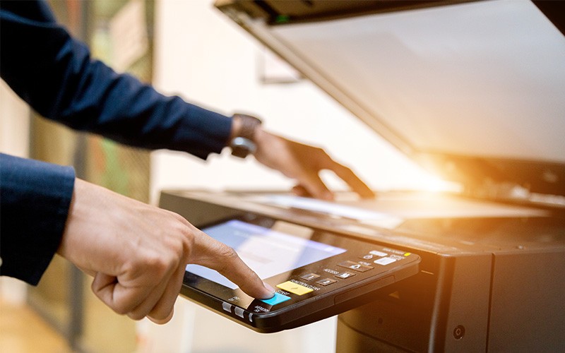 Enhance productivity while keeping costs in check Close up of hands using printer