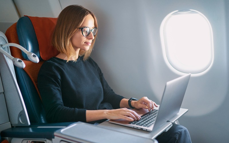 We’ll help you solve your business challenges Business woman on laptop device on airplane