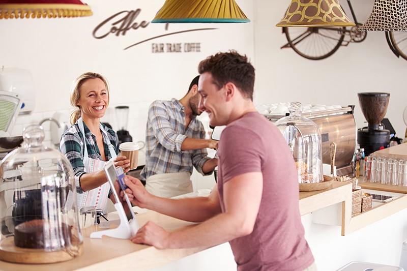 Equip your employees with advanced tools Smiling cafe worker rings up customer