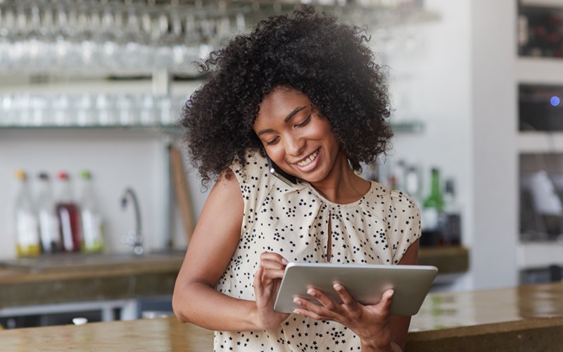 Customize a solution that boosts your operations Smiling small business owner on phone and tablet