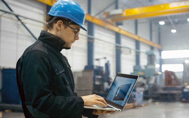 Streamline technology procurement and management Man in hard hat on laptop in warehouse
