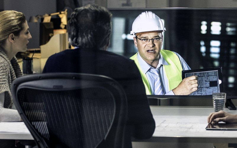 Support a smart and collaborative workforce Architect in hard hat on site video calling business team