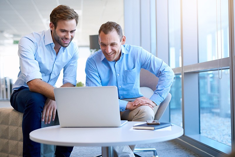 Modern and seamless experiences across your enterprise. Business professionals working together on laptop computer