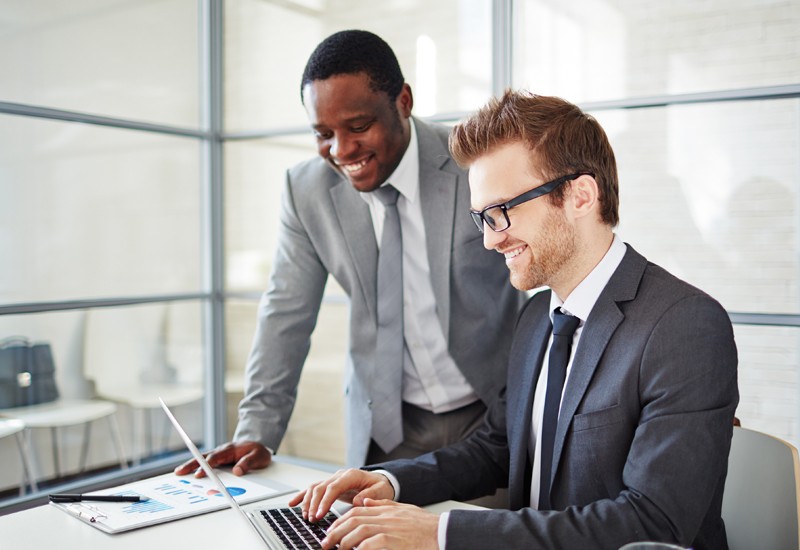 Contracts Manager Two businessmen look over laptop computer