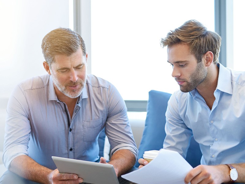 Hardware, software leasing services Business manager talking with direct report on couch in office holding technology financing agreements