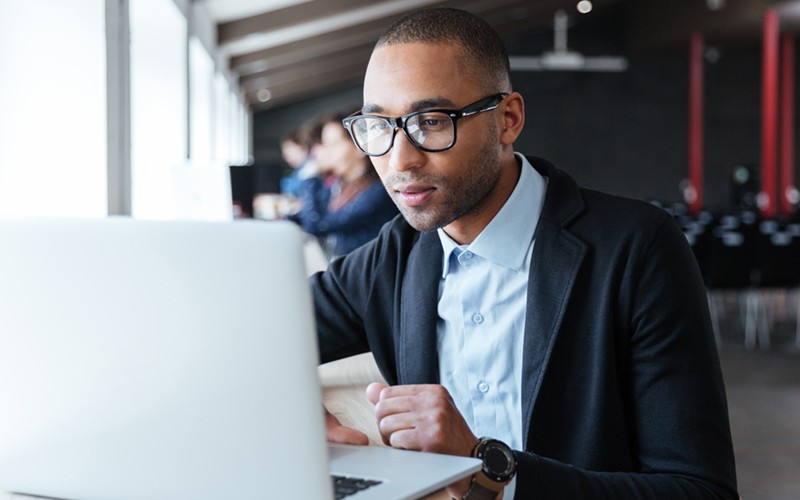 Our experts regularly assess your existing portfolio Businessman in glasses on laptop computer in open office