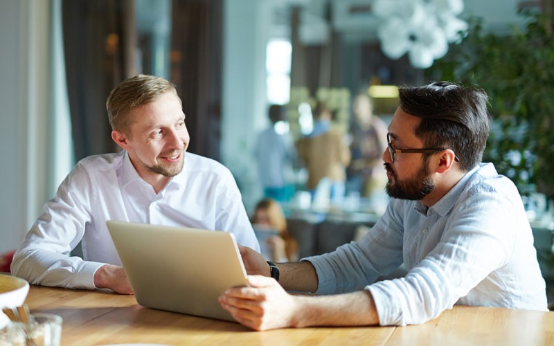 Invest smarter Two smiling businessmen discuss investments over tablet device