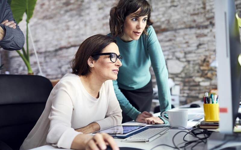 We’ll capture the right data from your environment Two businesswomen looking at reports on desktop computer