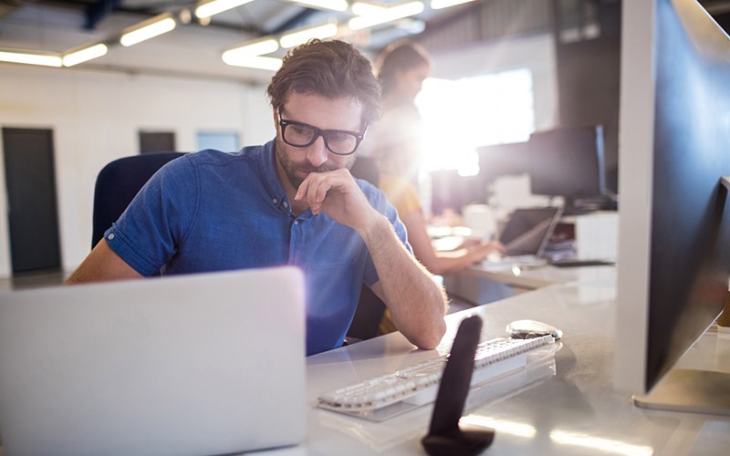 Optimize your software investments Serious businessman looking at software investments on laptop computer
