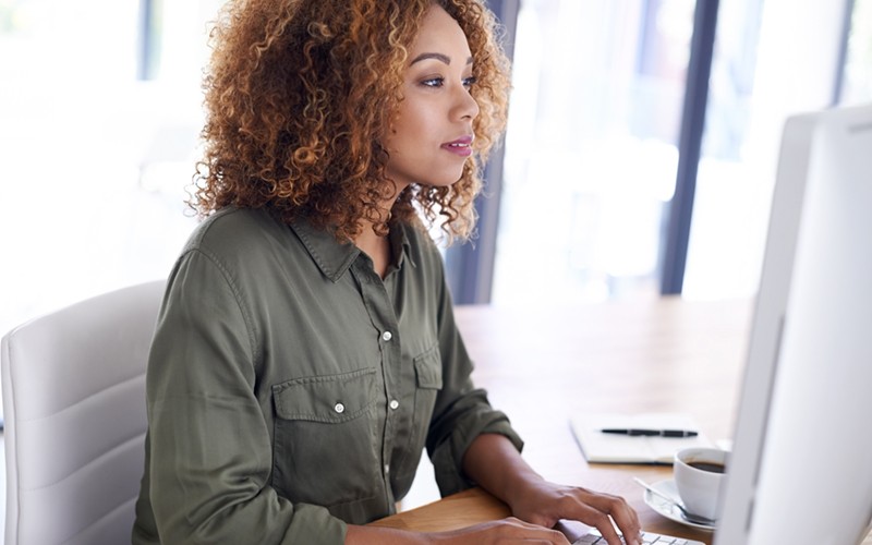 Businesswoman looking at budget information on desktop computer Businesswoman looking at budget information on desktop computer