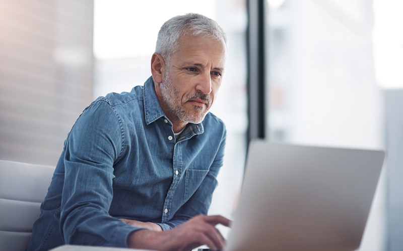 Review your entire application ecosystem Mature businessman working on laptop computer in bright office