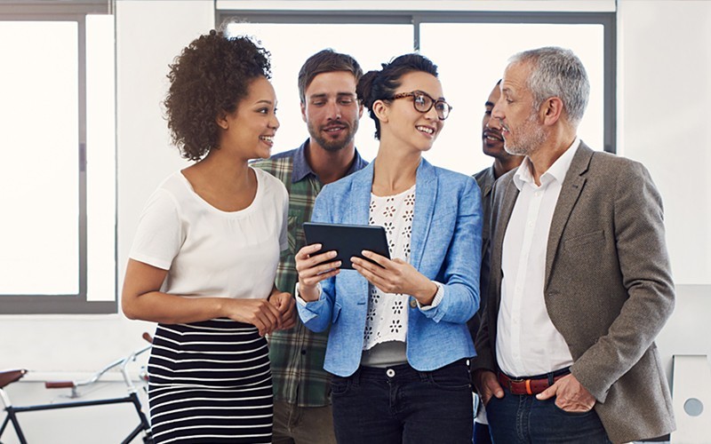 Manage your mobile workforce with ease. Two business colleagues use mobile tablet device