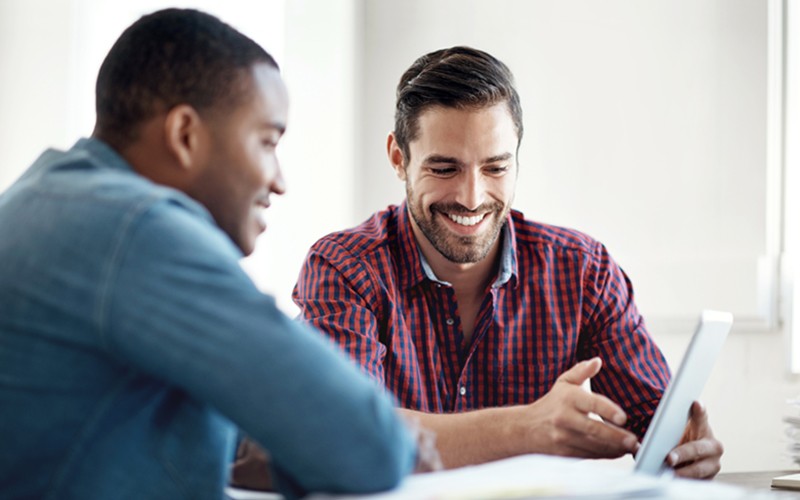 Manage your mobile workforce with ease. Two business colleagues use mobile tablet device